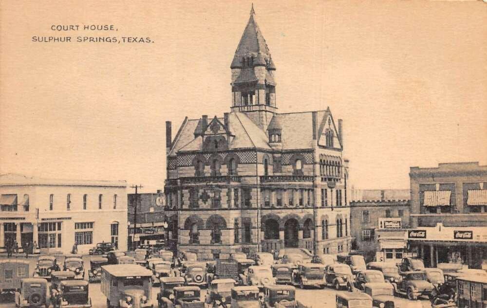 Historic courthouse in Sulphur Springs, Texas, with surrounding vintage cars.